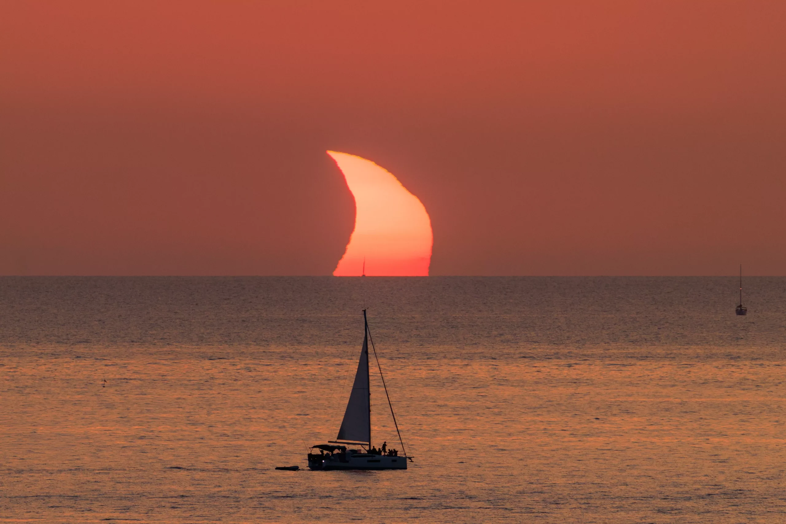 The crescent sun setting into the sea off Cala Tarida, Ibiza, during the August 2026 eclipse